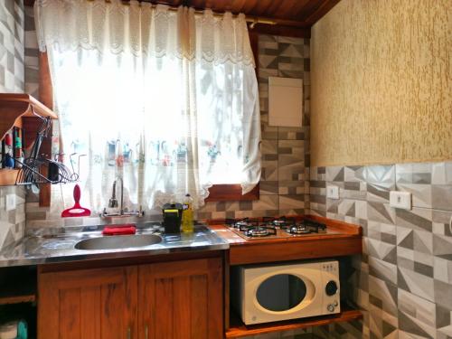 a kitchen with a sink and a microwave at CHALÉS LUAR DO PICO in Santo Antônio do Pinhal
