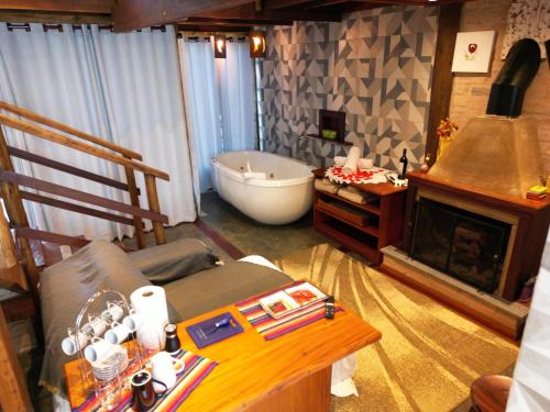 a living room with a tub and a couch and a fireplace at CHALÉS LUAR DO PICO in Santo Antônio do Pinhal