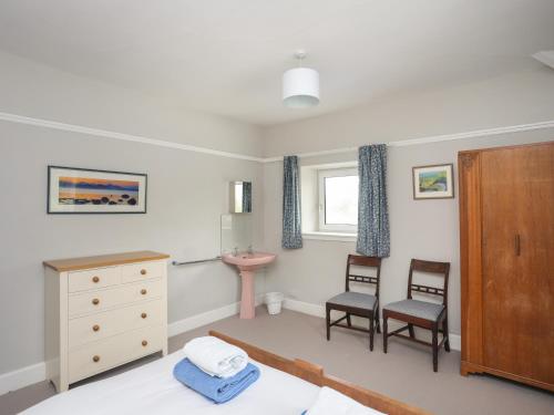 a bedroom with a bed and a dresser and two chairs at Nant Y Wyddan in Criccieth