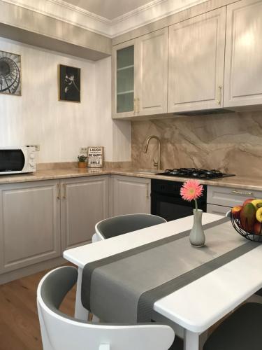 uma cozinha com armários brancos e uma mesa e cadeiras em Sunny Apart Hereditas em Ipoteşti