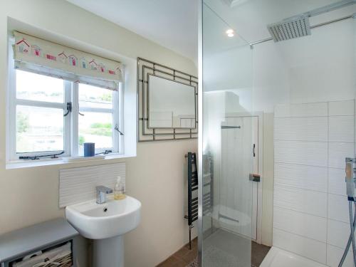 a white bathroom with a sink and a shower at The Barn House in Ugborough