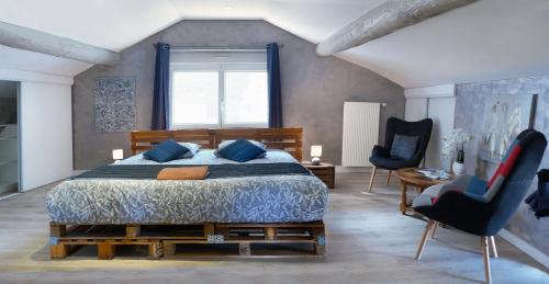 1 dormitorio con 1 cama grande y 2 sillas en Chambre d'hôte et gîte chez Thomas et John, en Verdún