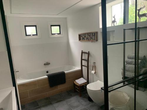 a bathroom with a bath tub and a toilet at Het Slakkenhuisje in Maarn