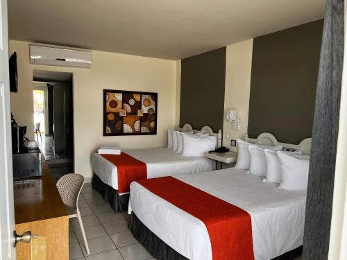 a hotel room with two beds and a television at HOTEL LOS ROBLES in Nuevo Laredo