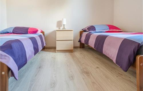 2 łóżka pojedyncze w pokoju z drewnianą podłogą w obiekcie 2 Bedroom Amazing Home In Ploskinia w mieście Płoskinie