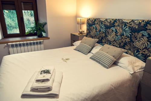 a large white bed with two towels on it at Apartamentos en el Valle del Jerte Flores para Angela in Cabezuela del Valle