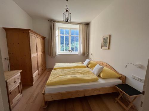 1 dormitorio con 1 cama con sábanas amarillas y ventana en Villa Quenz Family Suites, en Ortisei