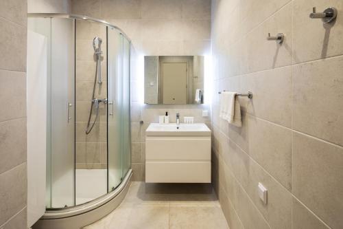 a bathroom with a shower and a sink and a mirror at Riverside Design Apartment with underground private parking in Rīga