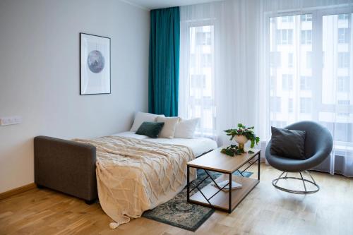 a bedroom with a bed and a chair and a table at Riverside Design Apartment with underground private parking in Rīga