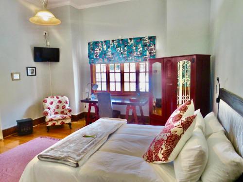 um quarto com uma cama e uma mesa num quarto em Whistlewood Guesthouse Walmer, Port Eizabeth em Port Elizabeth