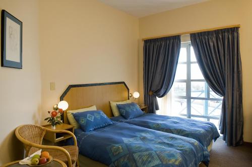 Schlafzimmer mit einem Bett mit blauer Bettwäsche und einem Fenster in der Unterkunft Sea-View Zum Sperrgebiet in Lüderitz