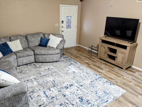 a living room with a couch and a flat screen tv at Mountain Views Near Sedona with Fenced Backyard in Cottonwood