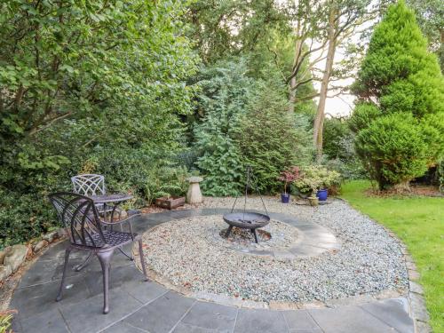 a patio with a barbecue and a chair and a fire pit at Taw River View in Okehampton