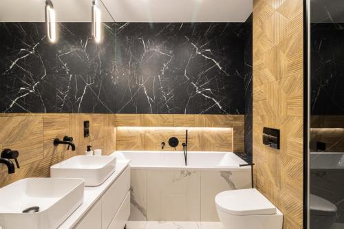 a bathroom with two sinks and a tub and a toilet at KOBIELA Luxury Aparthotel KTW City Center in Katowice
