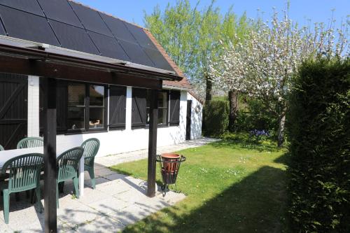 a house with two green benches and a solar roof at Bergh & Duin - lakens, elektriciteit en water inbegrepen in De Panne