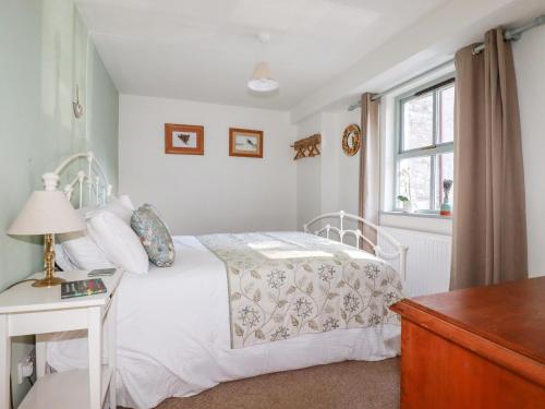 a bedroom with a white bed and a window at The Mews in Bodmin