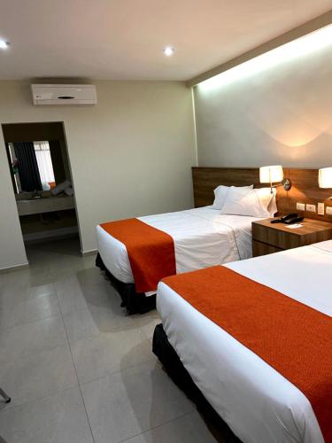 a hotel room with two beds and a bathroom at HOTEL LOS ROBLES in Nuevo Laredo