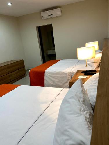 a hotel room with two beds and a table with a lamp at HOTEL LOS ROBLES in Nuevo Laredo