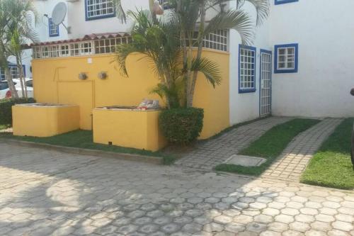 a yellow house with a palm tree in front of it at Casa en la zona de Acapulco diamante in La Sabana