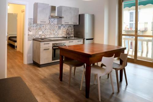 uma cozinha com uma mesa de madeira e cadeiras brancas em Kimimoel House em Turim