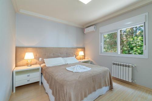 a bedroom with a bed with two night stands and a window at Apartamento Helena - Stay House Temporada in Canela