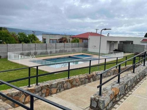 a swimming pool with a fence next to a building at Hermoso departamento con vista al mar in Tomé