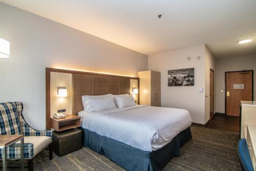 Holiday Inn Express Hotel & Suites Kalispell, an IHG Hotel في كاليسبيل: غرفة فندقية بسرير كبير وكرسي