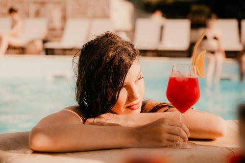 a woman sitting in a swimming pool with a drink at Cardinale Resort in Iaşi