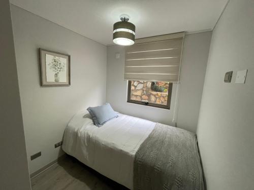 a bedroom with a bed with a blue pillow on it at Hermoso departamento con vista al mar in Tomé