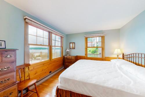1 dormitorio con 1 cama grande y 2 ventanas en Alton Bay Lakefront Beauty en Alton Bay
