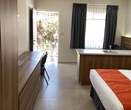a bedroom with a bed and a desk and a sink at HOTEL LOS ROBLES in Nuevo Laredo