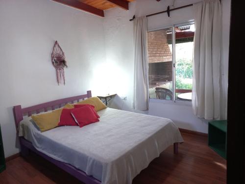 ein Schlafzimmer mit einem Bett mit zwei Kissen und einem Fenster in der Unterkunft Árbol de Oro - Terrafirme in Villa Yacanto