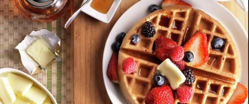 a plate of waffles with fruit on a table at Home2 Suites By Hilton Hammond in Hammond