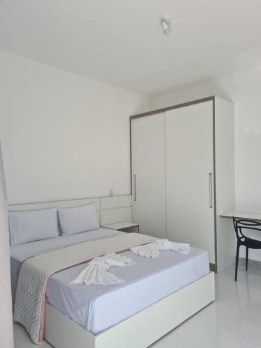a white bedroom with a large bed and a table at Escalada Hospedagens e Eventos in Mucugê