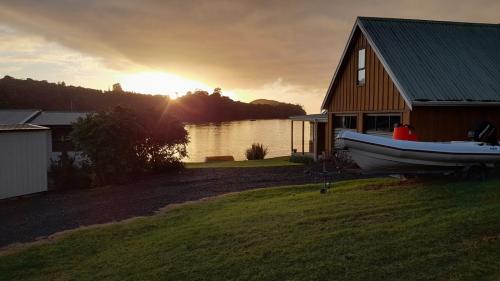 a boat is parked in front of a house at Marina Vista Cabin in Tutukaka