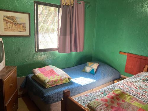 a green room with two beds and a window at Hostal Buena Vista in San Antonio