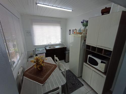 a small kitchen with a table and a microwave at CASA OTTON - Casa aconchegante, 3 quartos com cama de casal todos com ar condicionado in Gramado