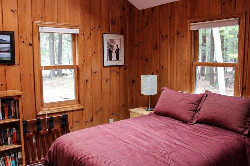 1 dormitorio con paredes de madera, 1 cama y 2 ventanas en Waterfront Delight near Fish Cove, en Meredith