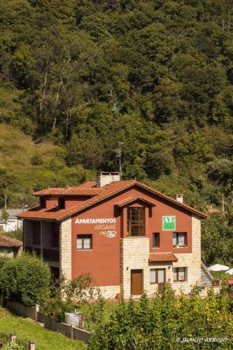 a building in front of a mountain with trees at Apartamentos Rurales Argame in Argamé