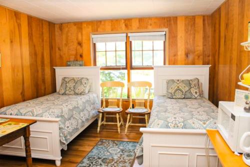 a bedroom with two beds and a table at Varney Point Studio in Gilford