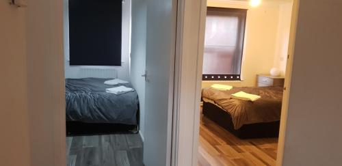 een kamer met 2 bedden en een deur naar een slaapkamer bij 2 Bedroom Cozy Chambers with free parking in Leeds