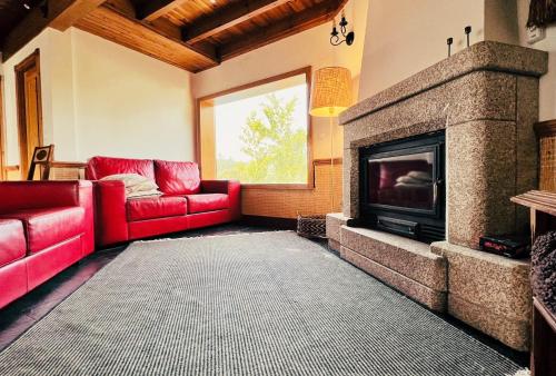 a living room with a red couch and a fireplace at Casa do Rio Alva in Arganil