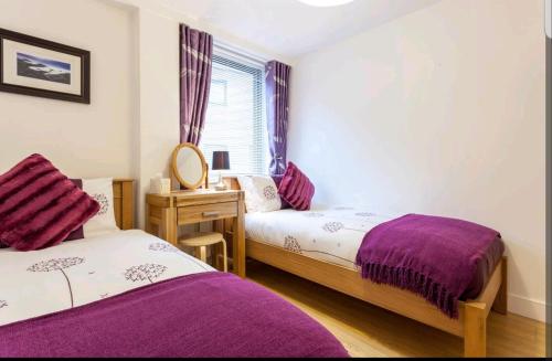 a bedroom with two beds and a desk and a window at Victoria Place apartment in Belfast
