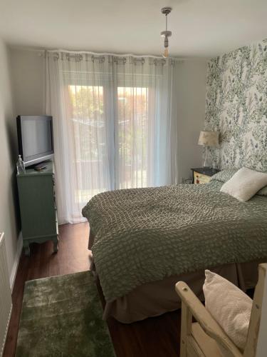 利奇菲爾德的住宿－Lichfield City Home，一间卧室设有一张床、一台电视和一个窗口。