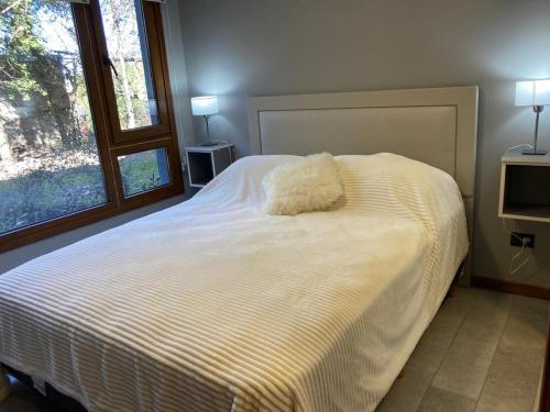 a white bed with a pillow on it in a bedroom at Alberti Desing in San Carlos de Bariloche