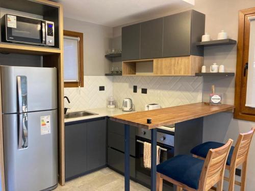 a kitchen with a refrigerator and a counter with chairs at Alberti Desing in San Carlos de Bariloche
