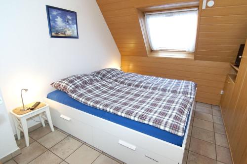 ein kleines Bett in einem kleinen Zimmer mit Fenster in der Unterkunft Ferienwohnung Doris in Norddeich