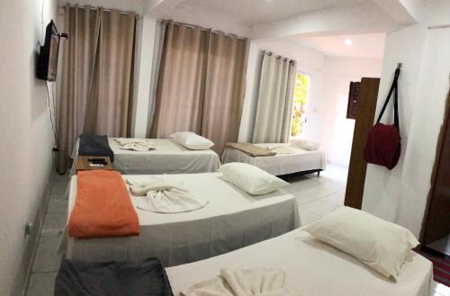 ein Hotelzimmer mit 3 Betten und einem TV in der Unterkunft Pousada Cruzeiro do Sul in São Miguel do Gostoso