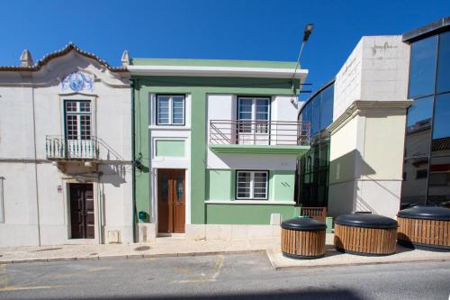 a green and white building with two trash cans in front of it at Graça Garden Torres Vedras in Torres Vedras