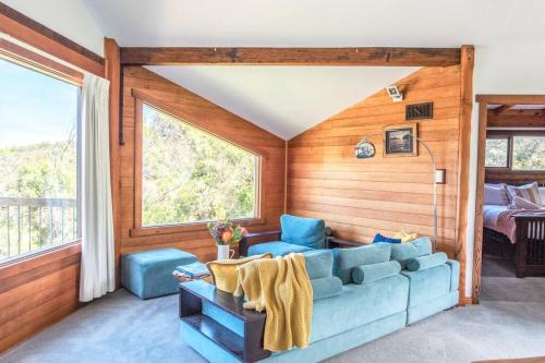 sala de estar con sofá azul y cama en Pixies at Eco Bay, en Port Campbell